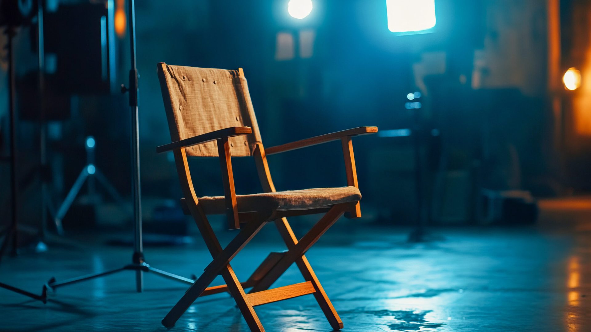 Empty director's chair on film set with studio lighting and equipment in background.