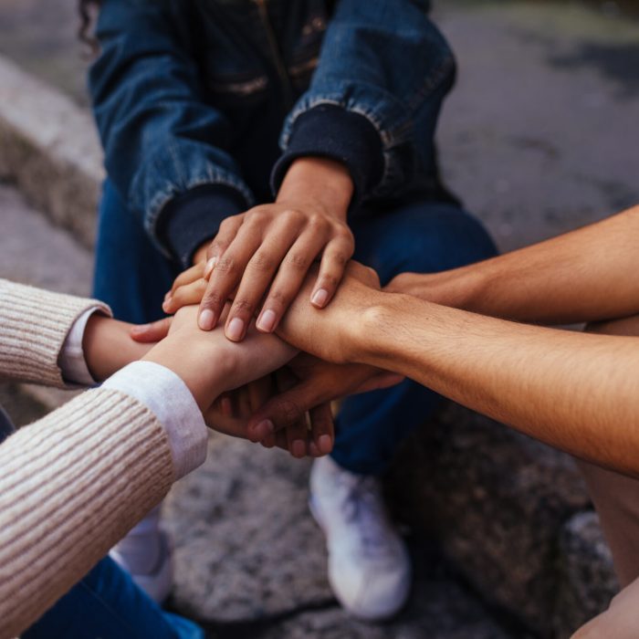 Unity and teamwork. Closeup image of young students making a stack of hands.